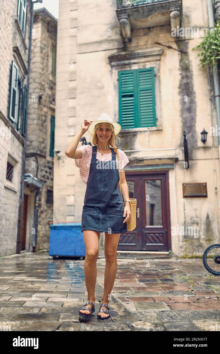 Elegante bionda in estate texas vestito posa di fronte a vecchi edifici. Stile di vita, moda, concetto di vacanza. Foto Stock
