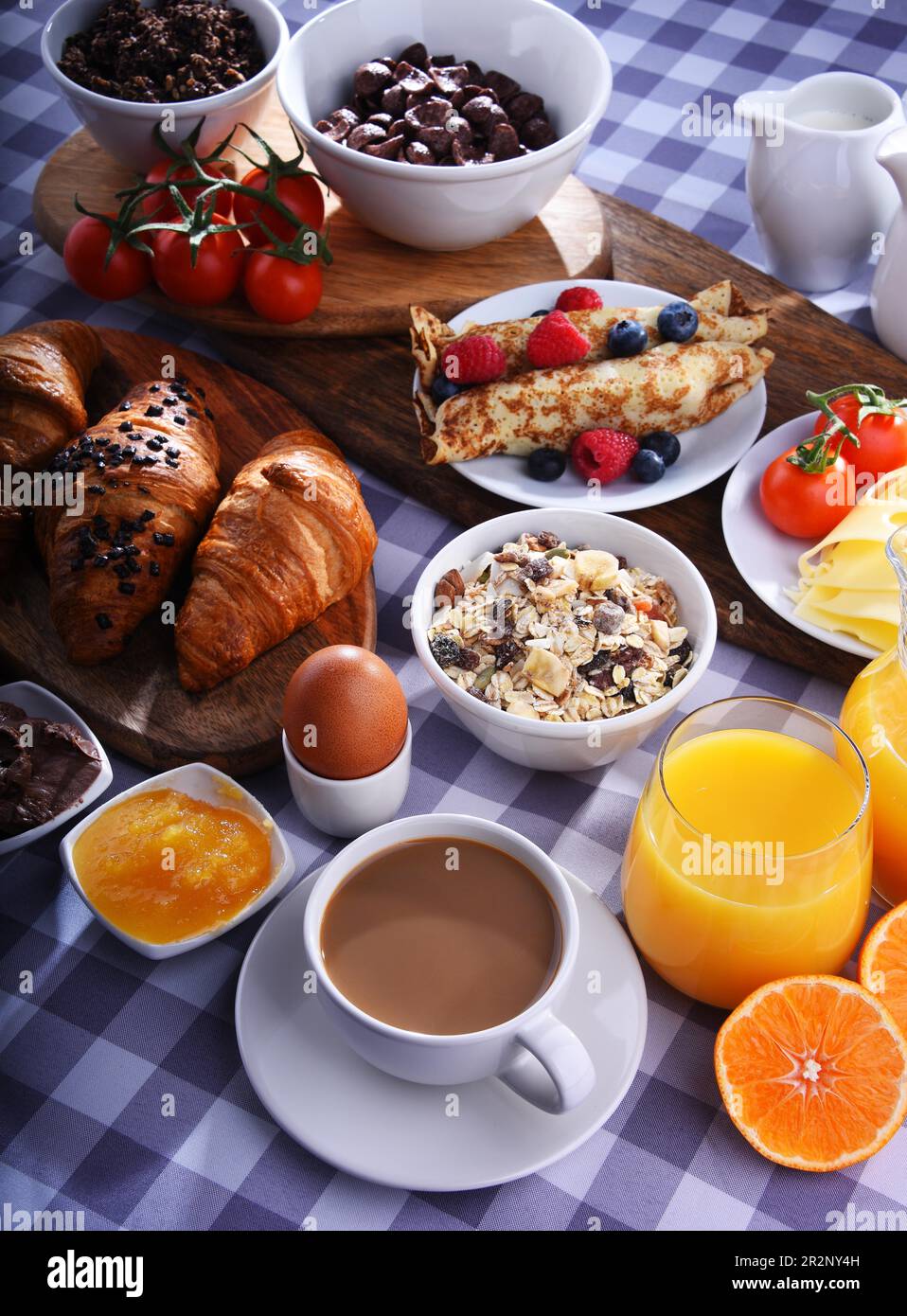 Colazione servita con caffè, succo d'arancia, croissant, pancake, uova, cereali e frutta Foto Stock