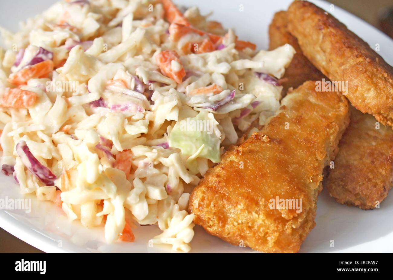 Pesce pastato dorato e croccante con un lato di cremoso insalata di cavoli fatta in casa Foto Stock