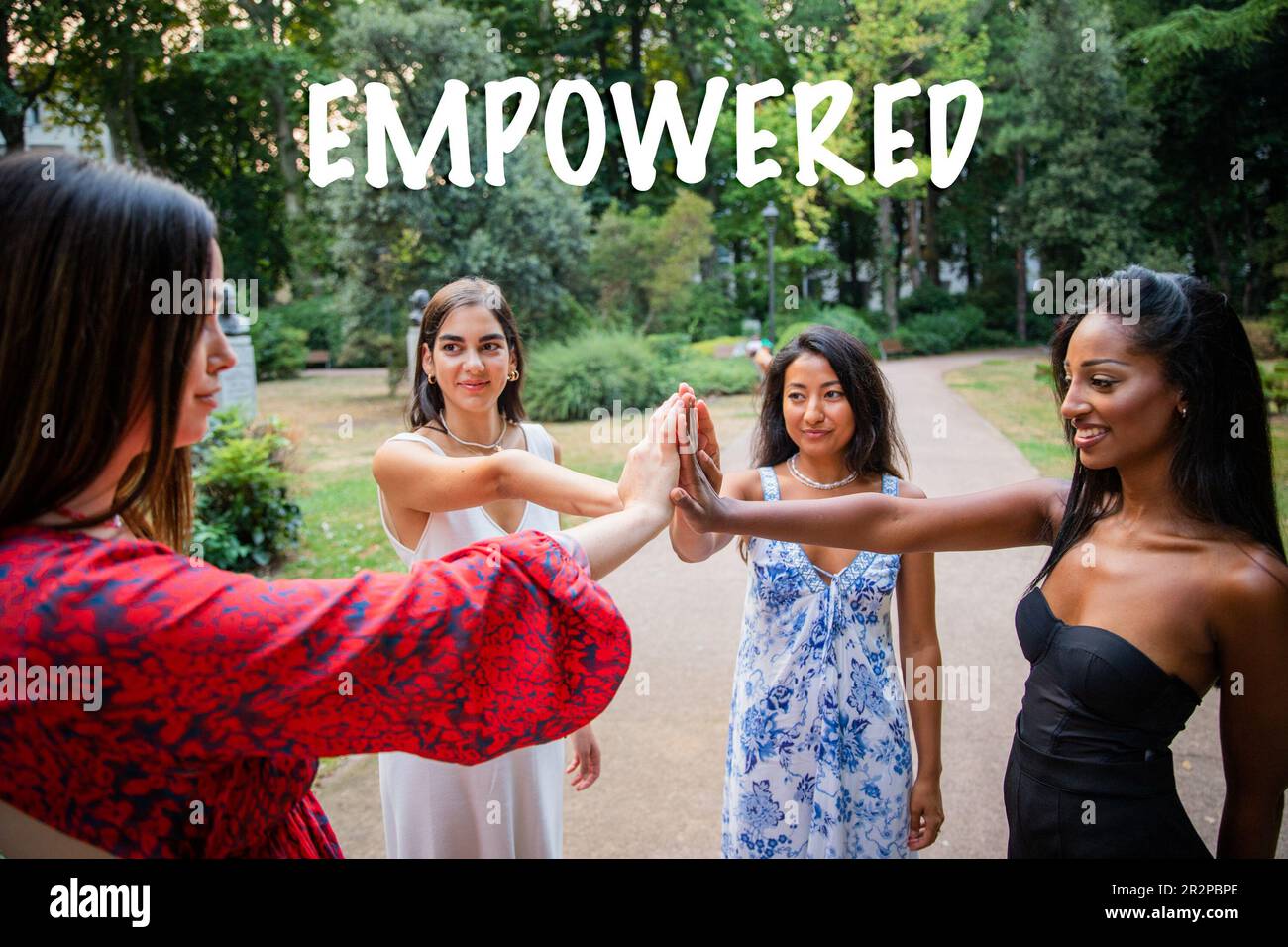 Quattro ragazze di diverse etnie con le mani unite in sostegno, donne responsabilizzate. Foto Stock
