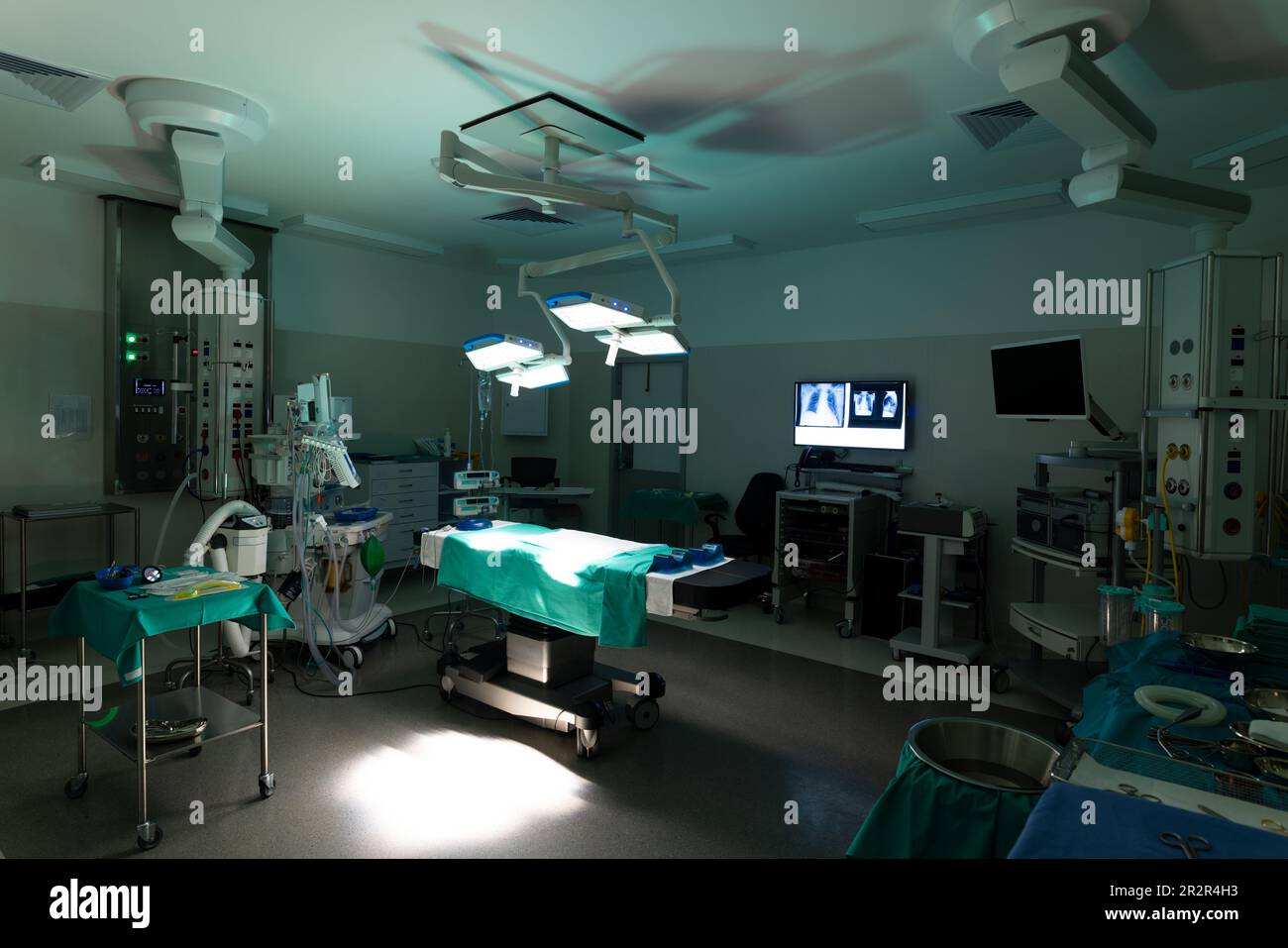 Vista generale della sala operatoria in ospedale, con tavolo operatorio e apparecchiature in condizioni di scarsa illuminazione Foto Stock