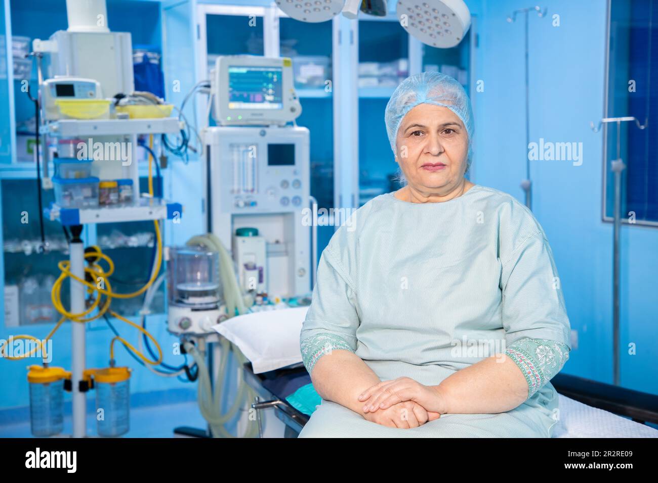 Ritratto di un paziente indiano anziano seduto in teatro operatorio pronto per l'intervento chirurgico in ospedale. Concetto sanitario e medico. Foto Stock