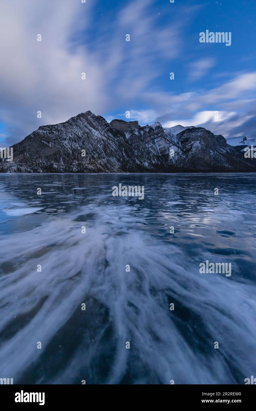 Modelli nel ghiaccio del lago Minnewanka con il Monte Inglismaldie nel Parco Nazionale di Banff sullo sfondo al crepuscolo Foto Stock