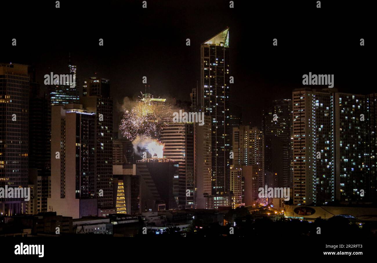 Fuochi d'artificio sparati dal tetto di un edificio tra i grattacieli del centro della città a Makati, il moderno quartiere finanziario di Metro Manila, skyline di notte Foto Stock