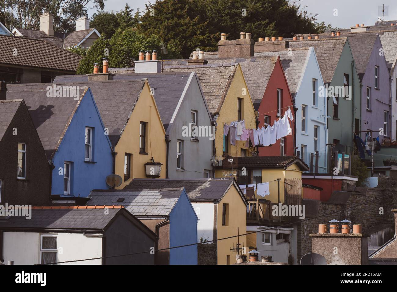Una fila di case colorate sulla città irlandese di Cobh, paesaggio urbano. Accogliente architettura europea. La lavanderia viene asciugata su un mantello. Foto Stock