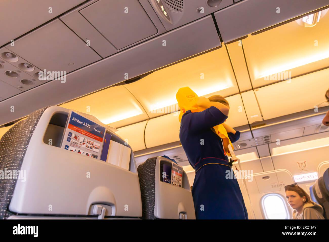 Un assistente di volo che dimostra giubbotto di salvataggio ai passeggeri in un aereo Airbus A320 operato da Fly Arna Foto Stock