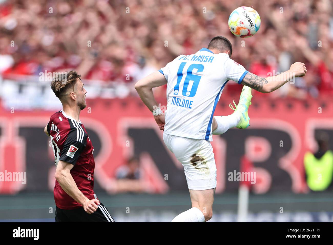 Norimberga, Germania. 21st maggio, 2023. Calcio: 2. Bundesliga, 1. FC Nürnberg - Hansa Rostock, 33. giornata di incontro al Max-Morlock-Stadion. Lukas Schleimer (l) di Norimberga combatte per la palla con Ryan Malone di Hansa Rostock. Credit: Daniel Karmann/dpa - NOTA IMPORTANTE: In conformità ai requisiti della DFL Deutsche Fußball Liga e del DFB Deutscher Fußball-Bund, è vietato utilizzare o utilizzare fotografie scattate nello stadio e/o della partita sotto forma di sequenze di immagini e/o serie di foto simili a video./dpa/Alamy Live News Foto Stock