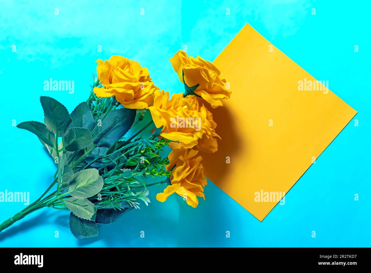 Bouquet di rose gialle e carta gialla su fondo blu Foto Stock