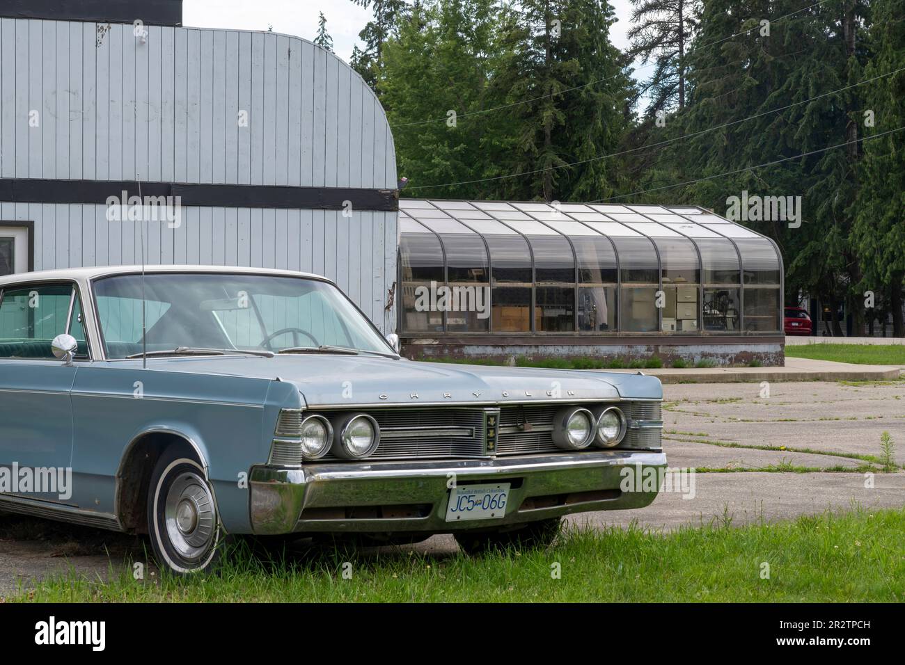 Sicamouse, BC, Canada-Agosto 2022; Vista del terreno e della costruzione di una cena ora chiusa e fatiscente con un classico Chrysler New Yorker parcheggiato in Foto Stock