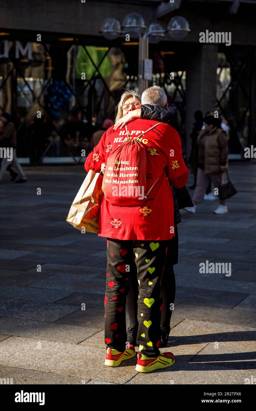 Indossando una giacca con l'iscrizione Happy Healing abbraccia un uomo si trova di fronte alla cattedrale per dare un abbraccio alla gente, Colonia, Germania. Mit einer Jack Foto Stock