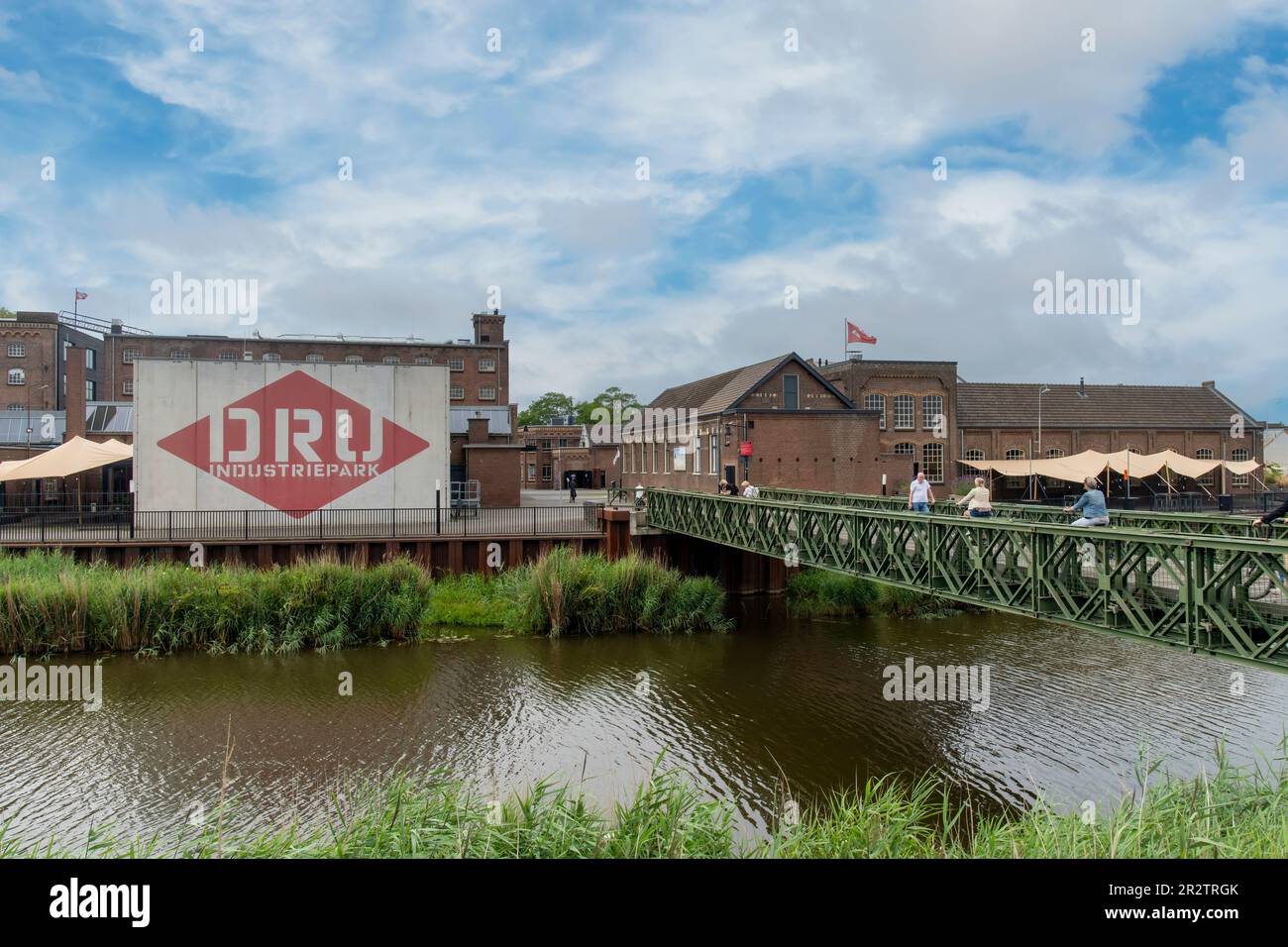 Ulft, Paesi Bassi-Agosto 2022; Vista del ponte sul fiume Oude IJssel verso la DRU Culture Factory, una vecchia fabbrica di ghisa ristrutturata Foto Stock
