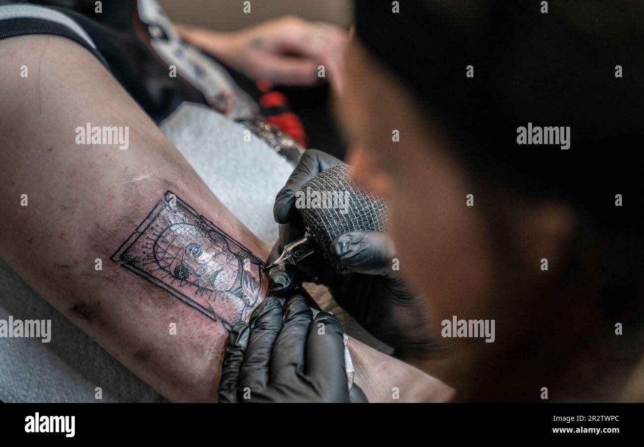 Una donna ottiene un tatuaggio di Pinhead da Hellraiser durante HorrorconUK al Magna Science Adventure Centre a Rotherham. Data immagine: Domenica 21 maggio 2023. Foto Stock