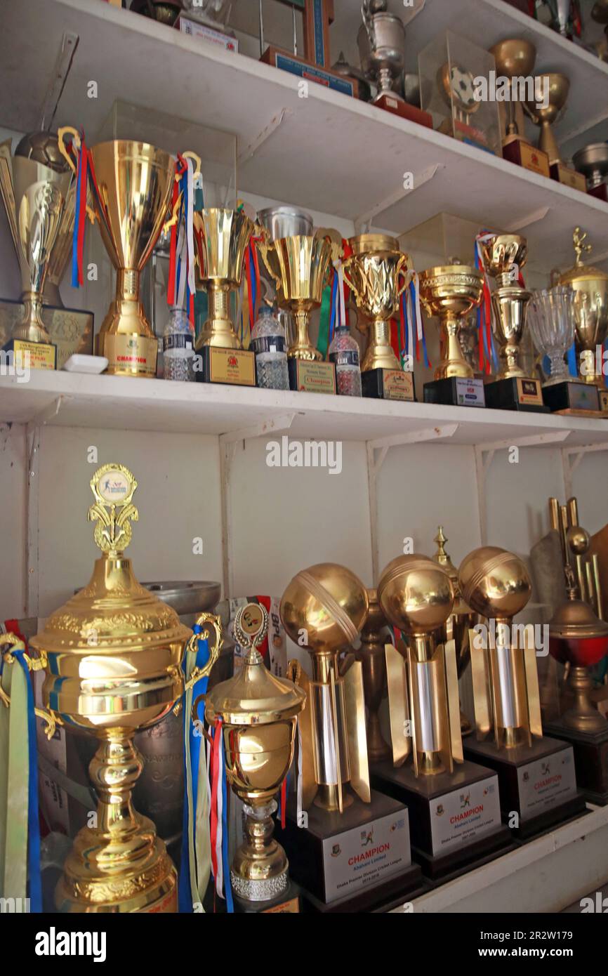 I trofei per i tornei vincenti in vari momenti vengono visualizzati nella sala del consiglio di amministrazione di Abahani Ltd. Club come calciatori partecipano alla sessione di parctice al club groun Foto Stock