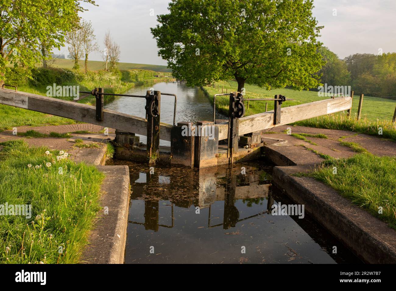 Blocca e blocca i cancelli a Tyrley Locks sul canale Shropshire Union in Inghilterra. Alberi riflessi in acqua ferma in una mattina di sole Foto Stock
