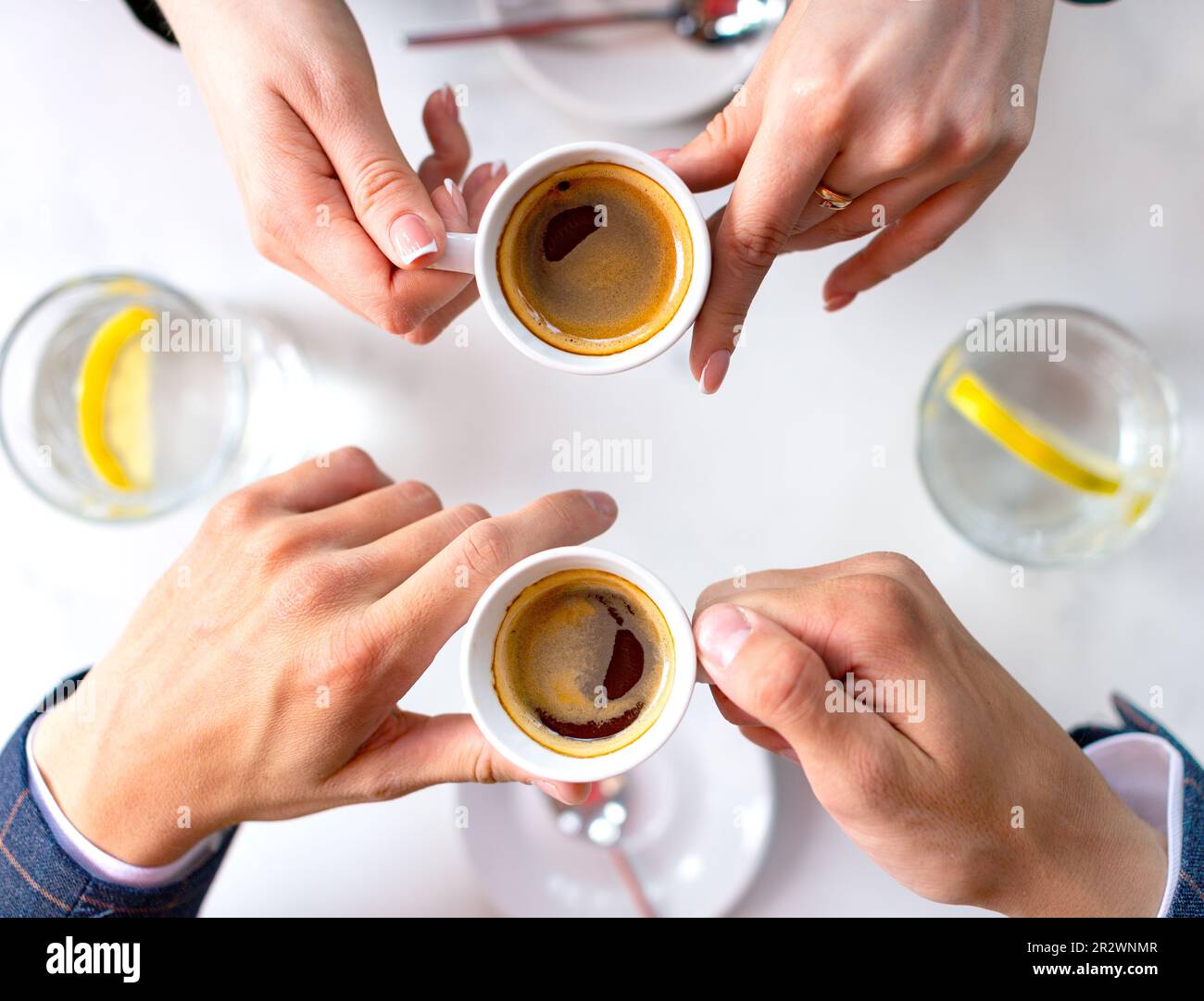 Mani di un uomo e di una donna durante una pausa caffè. I colleghi comunicano e discutono gli eventi. Amicizia e comunicazione senza pregiudizio. Vista dall'alto. Foto Stock