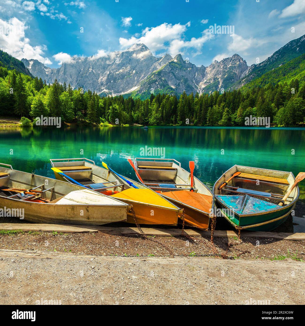 Posto fantastico con colorate barche a remi sul lago Fusine e bellissime montagne nebbiose sullo sfondo, Italia, Europa Foto Stock