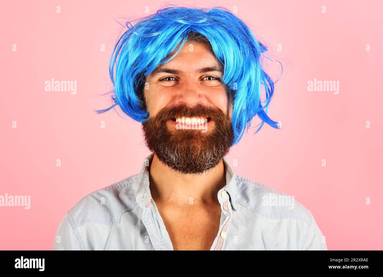 Uomo sorridente in parrucca blu. Uomo felice con barba e baffi in parrucca colorata. Ragazzo elegante con capelli blu. Maschio barbuto in parrucca. Uomo in pericolo. Emozione Foto Stock