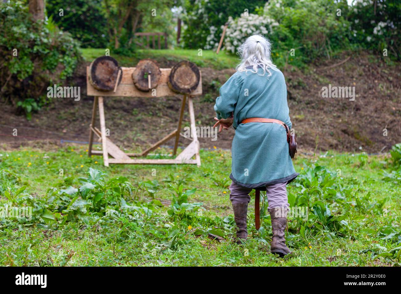 Uomo di epoca medievale che pratica l'ascia gettando su tre bersagli. Foto Stock