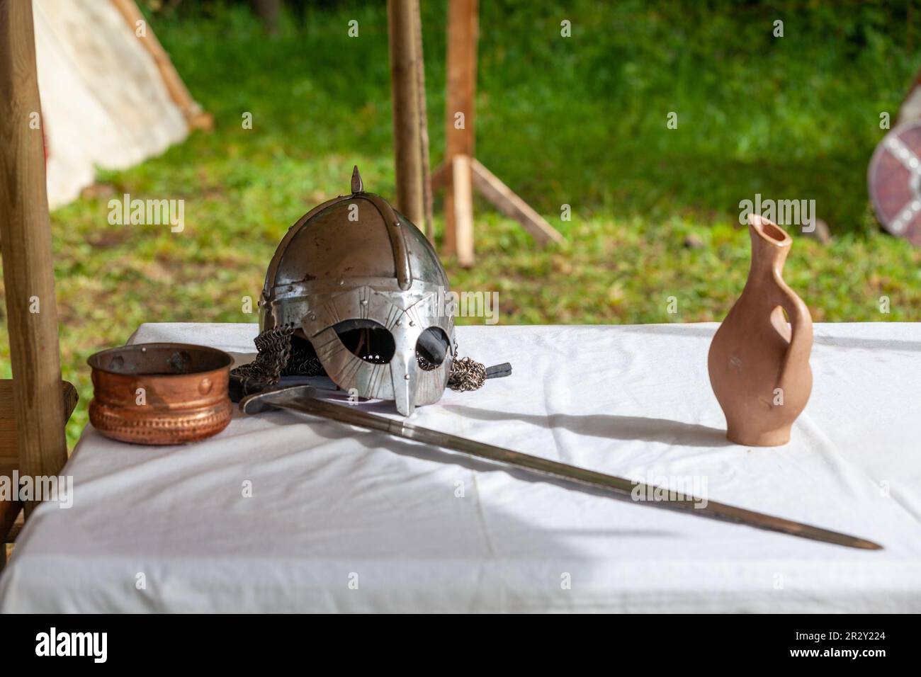 Un casco vichingo e una spada posati sulla tavola di un campo. Foto Stock