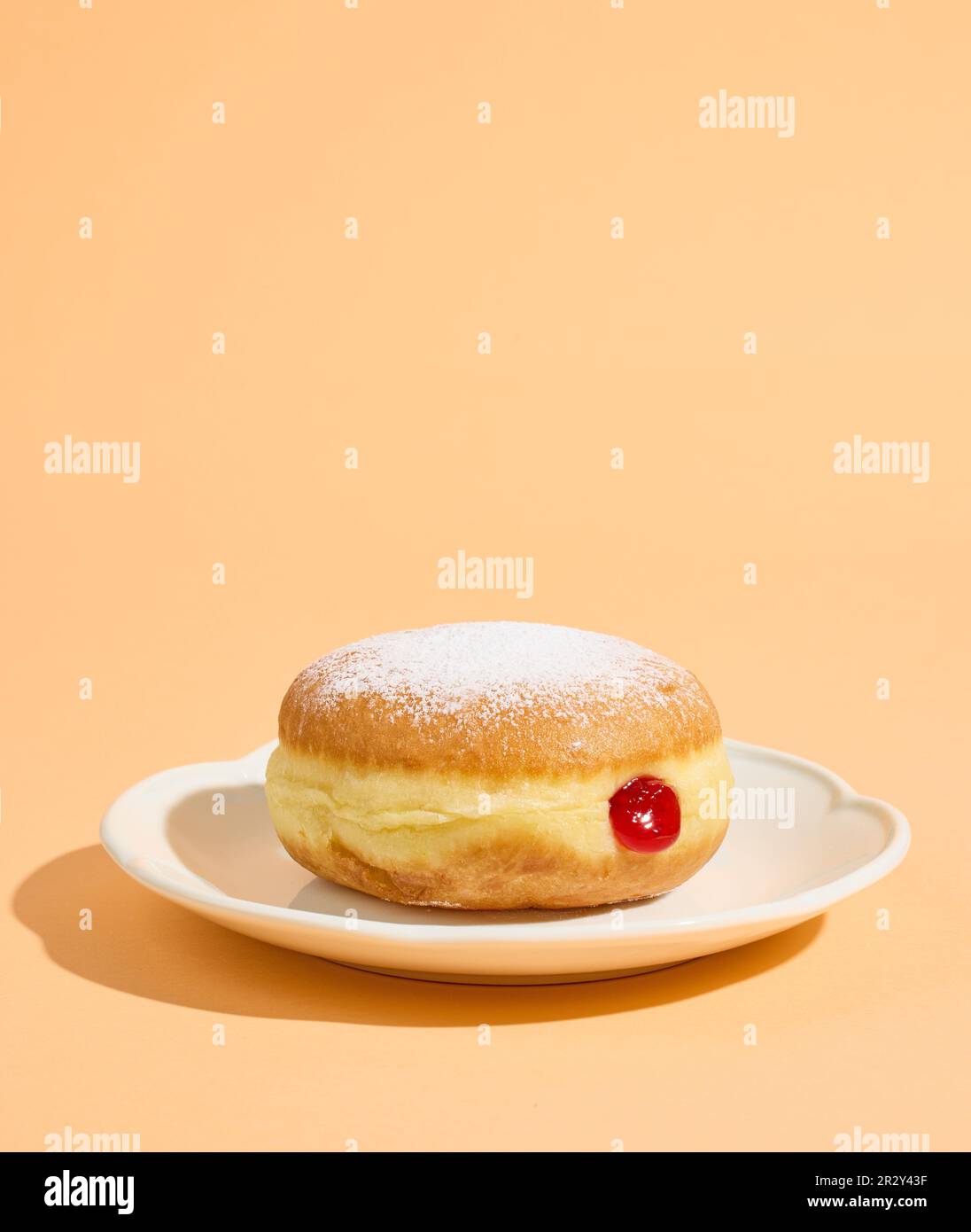 ciambella di gelatina appena sfornata su piastra bianca isolata su fondo arancione Foto Stock