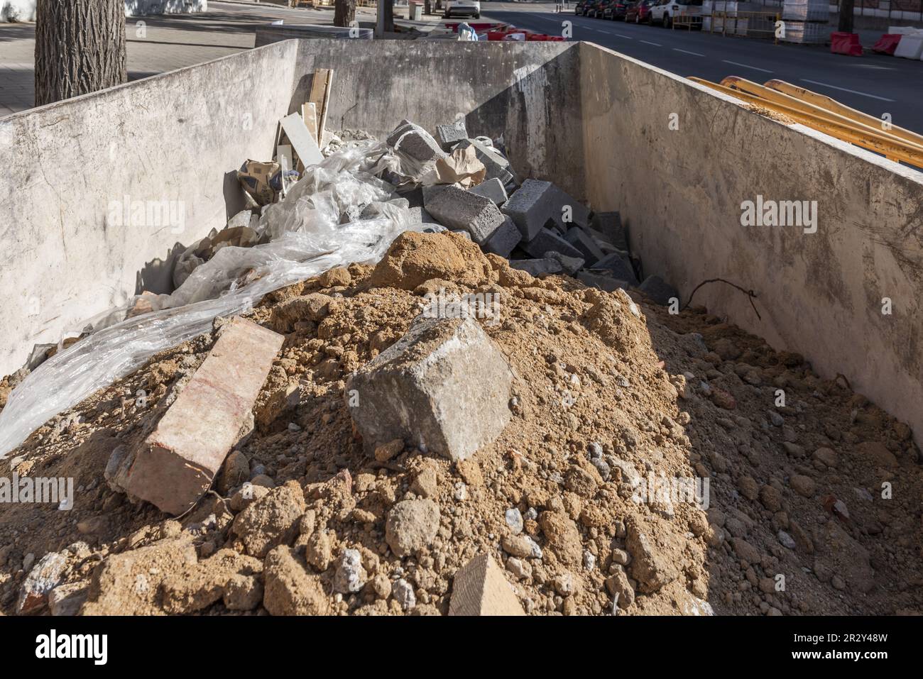 Un contenitore di metallo parcheggiato sulla strada pieno di rifiuti provenienti da un cantiere edile nelle vicinanze Foto Stock