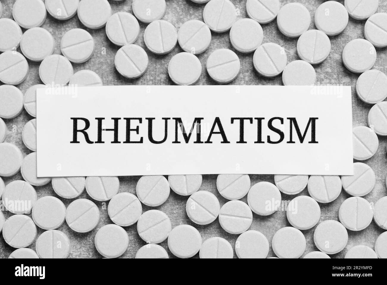 Scheda con parola Rheumatism e pillole su sfondo grigio chiaro, piatto Foto Stock