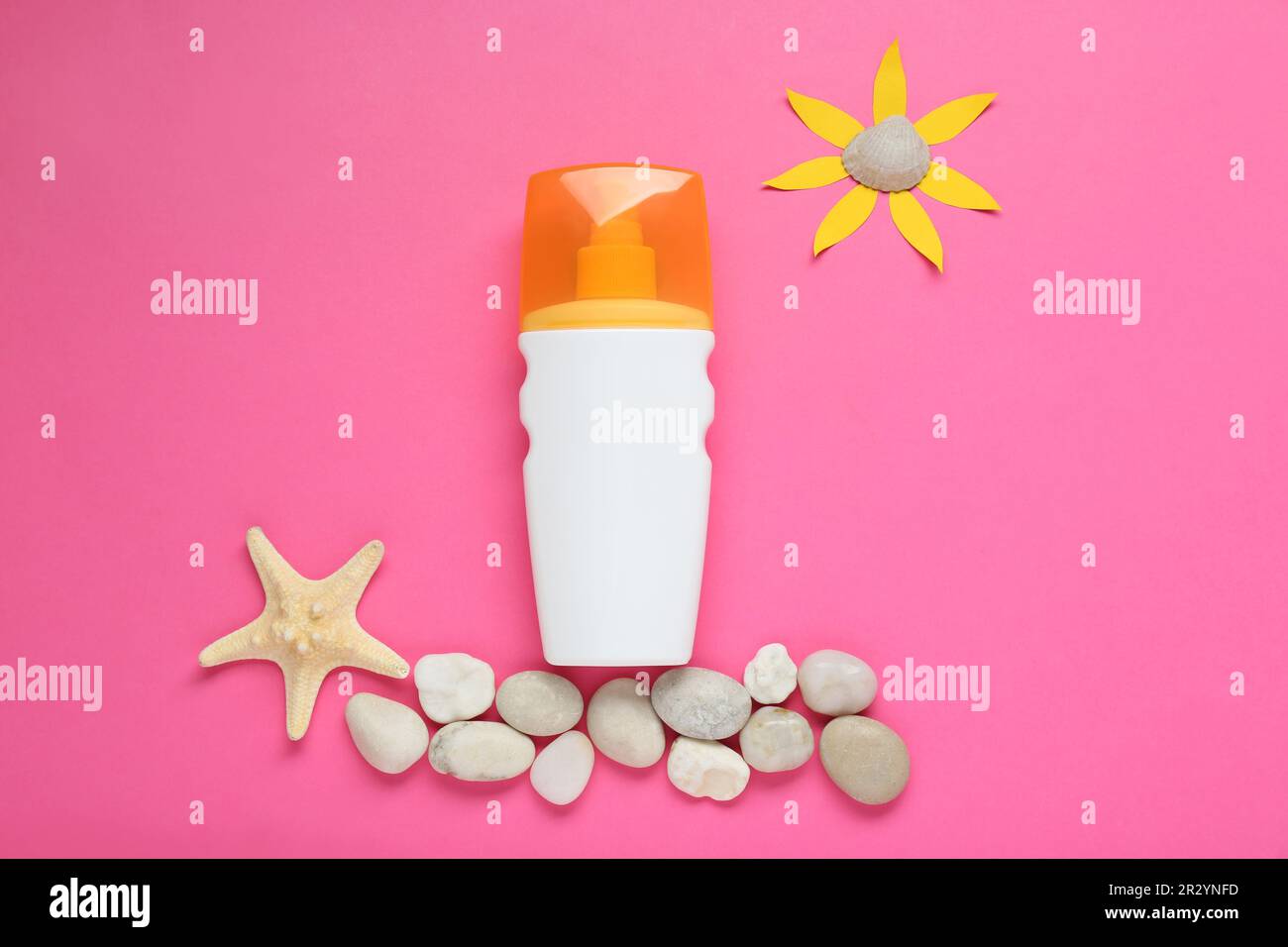 Crema solare, sole di carta e conchiglie su sfondo rosa, giacitura piatta Foto Stock