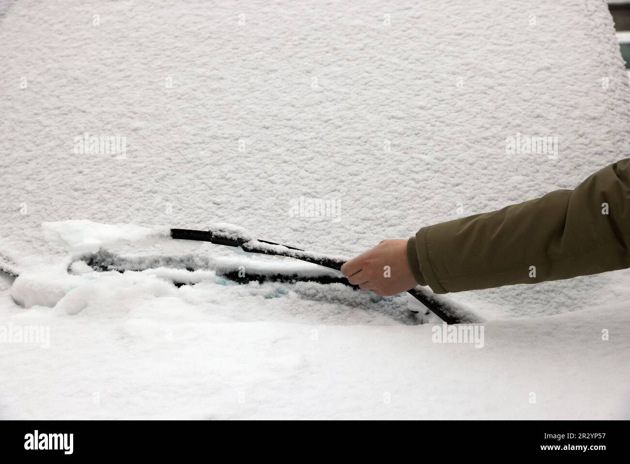 Donna pulizia spazzola tergicristallo auto coperta di neve, primo piano Foto Stock