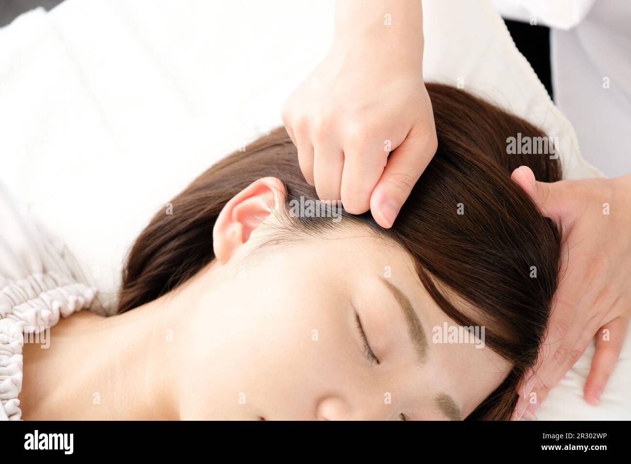 Una donna riceve pressione sui suoi templi in una clinica di agopuntura Foto Stock