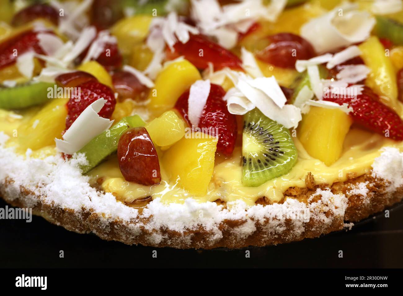 Torta cremosa con fragole fresche, pesche e kiwi, focus selettivo. Dessert alla crema dolce con cioccolato bianco grattugiato Foto Stock