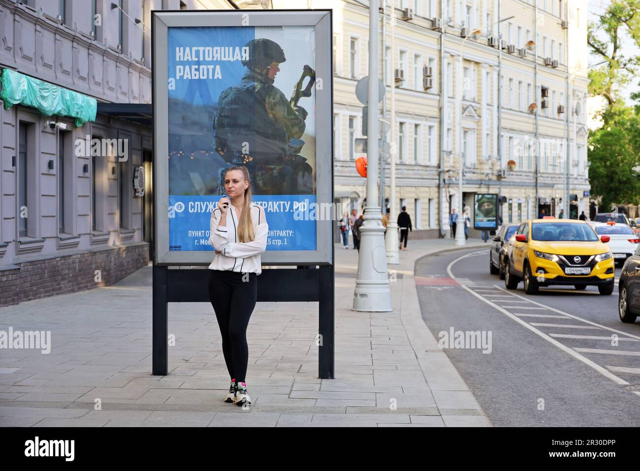 Ragazza in piedi vicino al poster con una chiamata per il servizio di contratto nell'esercito russo su strada città Foto Stock