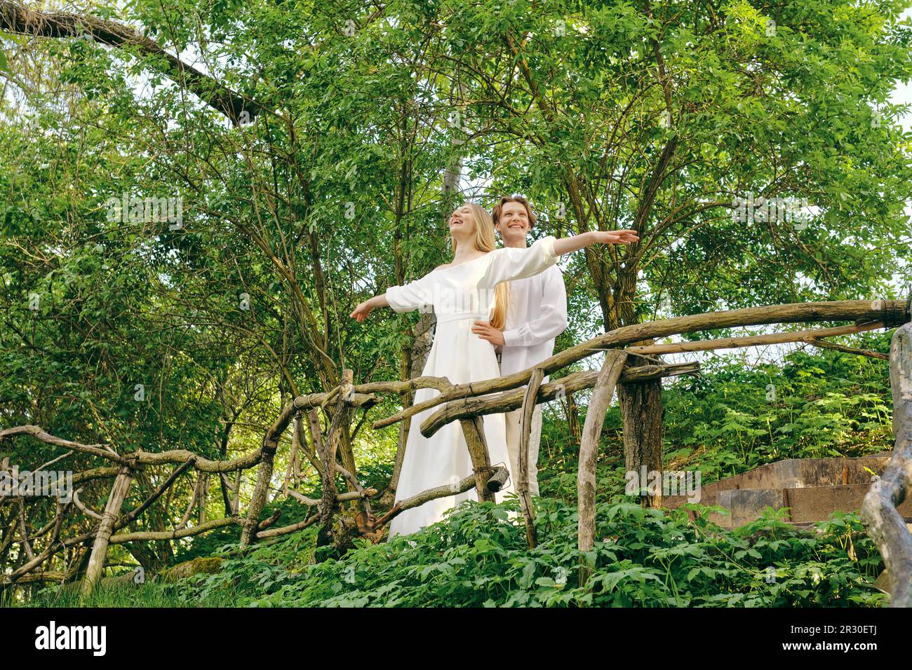 La donna felice si trova sulla scogliera, stendendo le braccia a lato, e il suo uomo tiene la vita Foto Stock
