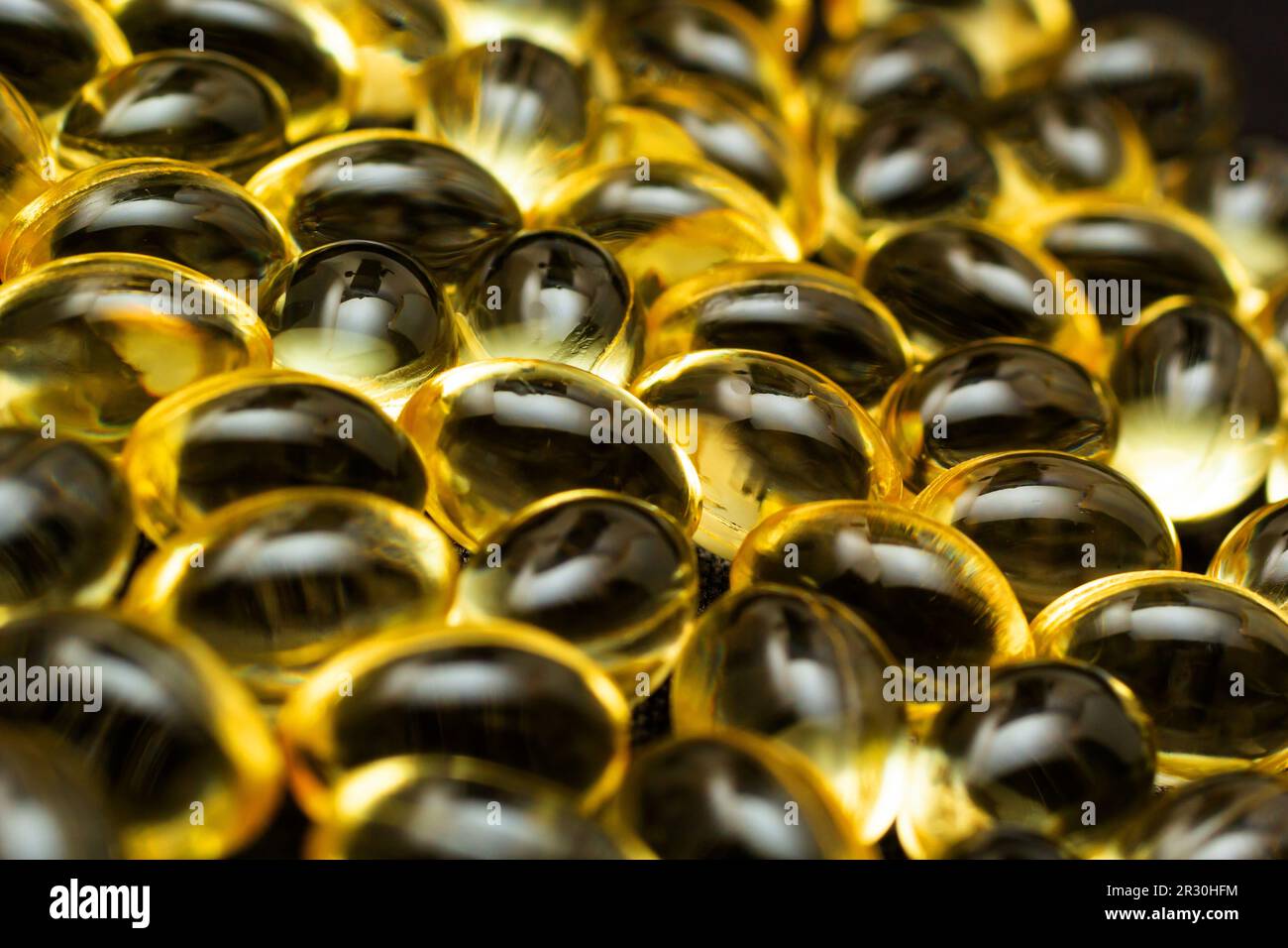 Macro primo piano della capsula di gel Omega 3 su sfondo nero riflettente. Foto Stock