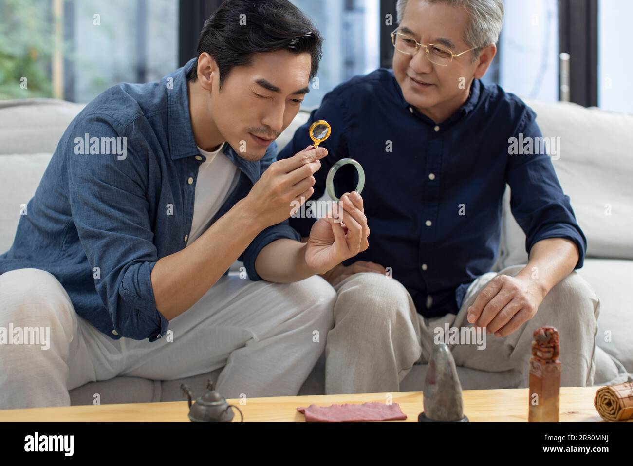 Uomo cinese medio-adulto che ammira gli oggetti d'antiquariato con suo padre Foto Stock