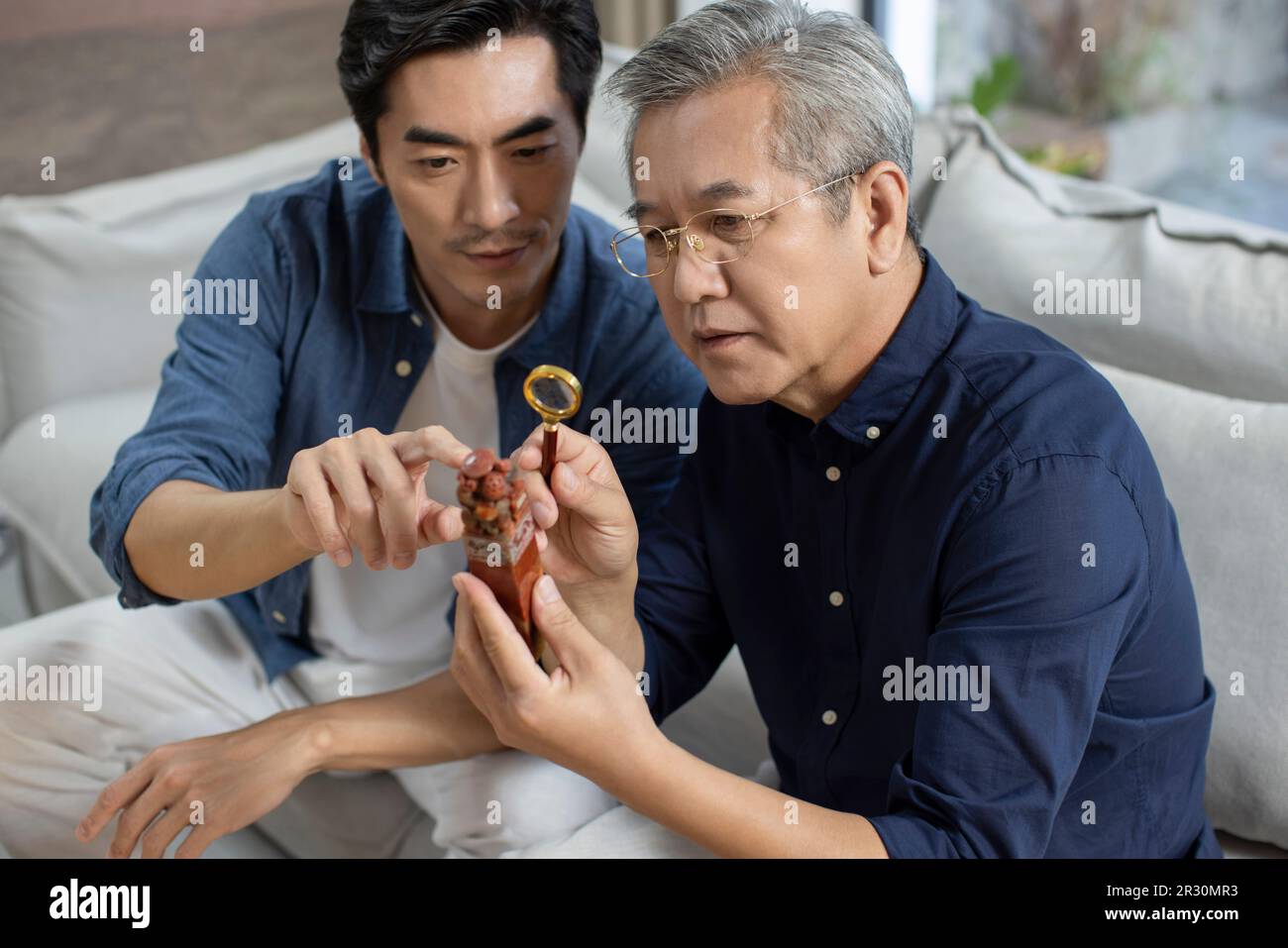 Uomo cinese medio adulto che ammira l'antiquariato con suo padre Foto Stock