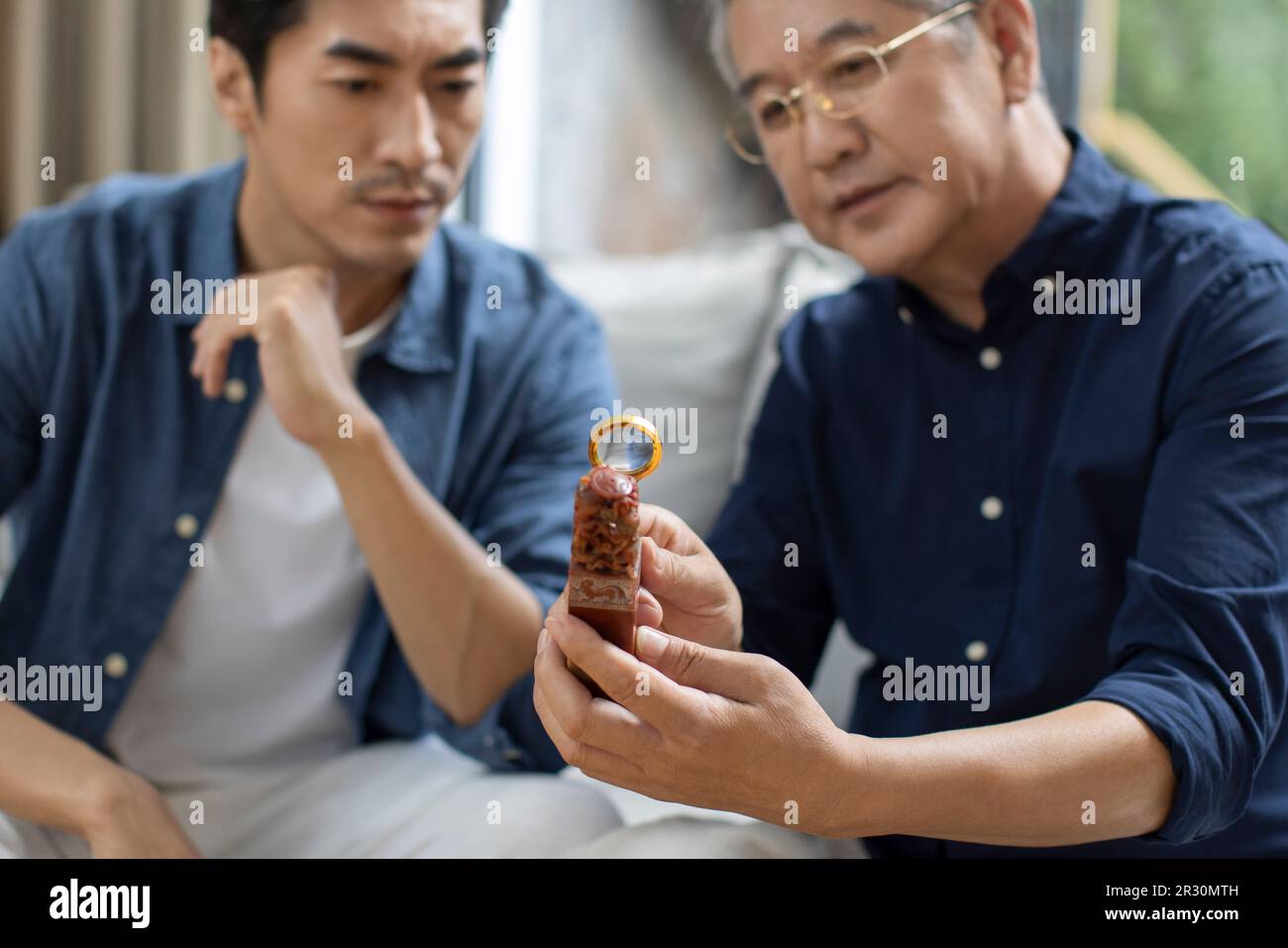 Uomo cinese medio adulto che ammira l'antiquariato con suo padre Foto Stock