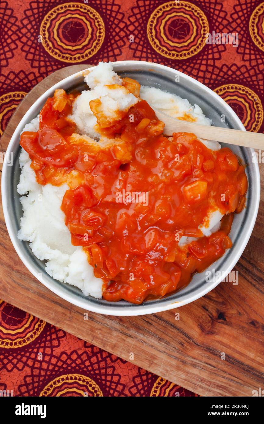 Tradizionale panino sudafricano o pasto di mais con salsa tradizionale di pomodoro e cipolla su tessuto tradizionale Foto Stock