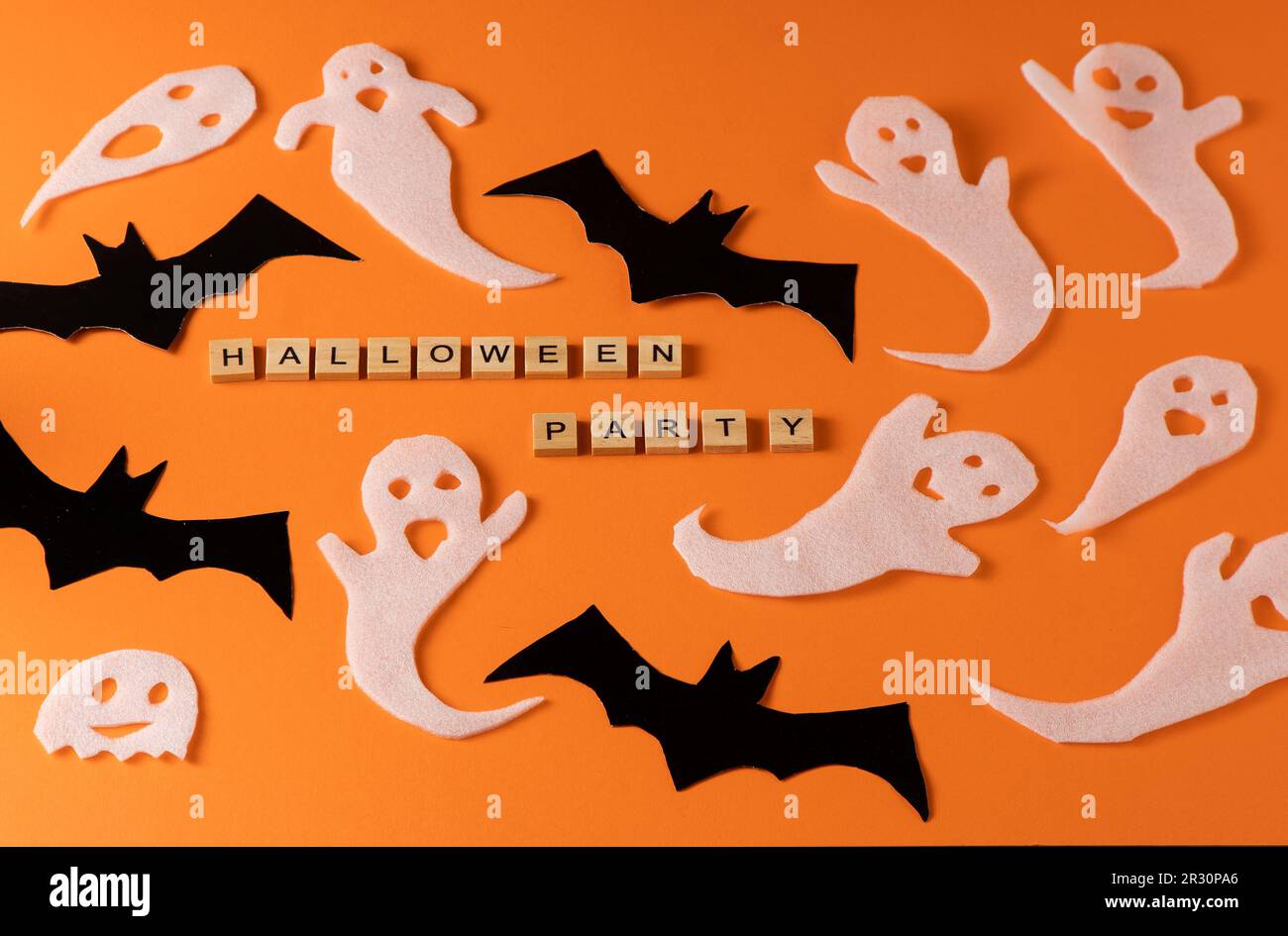 Fantasmi bianchi e mazza per la festa di Halloween. Immagine fantasma della carta di avvolgimento su sfondo arancione vista dall'alto. Fumetto Creepy Whisper. Fai-da-te fatto a mano. Impostare i caratteri boo. Parola frase di legno della lettera. Foto Stock