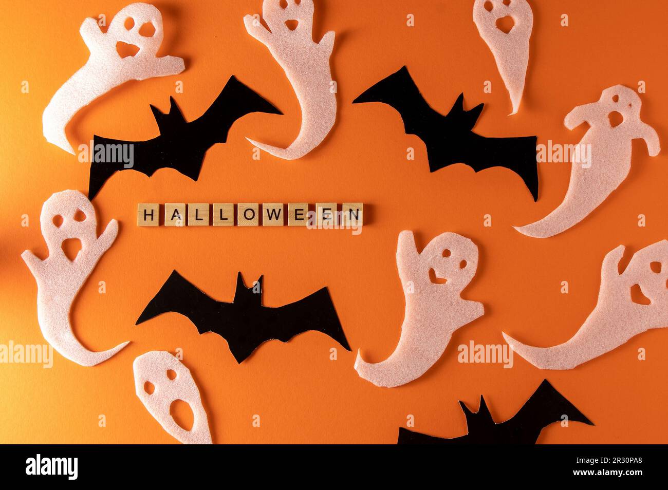 Fantasmi bianchi e mazza per la festa di Halloween. Immagine fantasma della carta di avvolgimento su sfondo arancione vista dall'alto. Fumetto Creepy Whisper. Fai-da-te fatto a mano. Impostare i caratteri boo. Parola frase di legno della lettera. Foto Stock