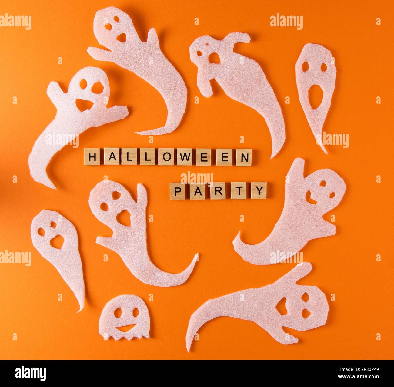 Fantasmi bianchi per la festa di Halloween. Immagine fantasma della carta di avvolgimento su sfondo arancione vista dall'alto. Fumetto Creepy Whisper. Fai-da-te fatto a mano. Impostare i caratteri boo. Parola frase di legno della lettera. Foto Stock