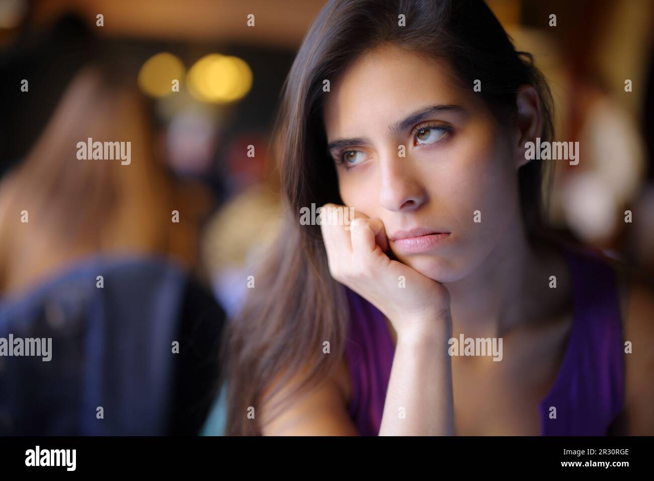 Annoiato donna in attesa in un ristorante interno Foto Stock