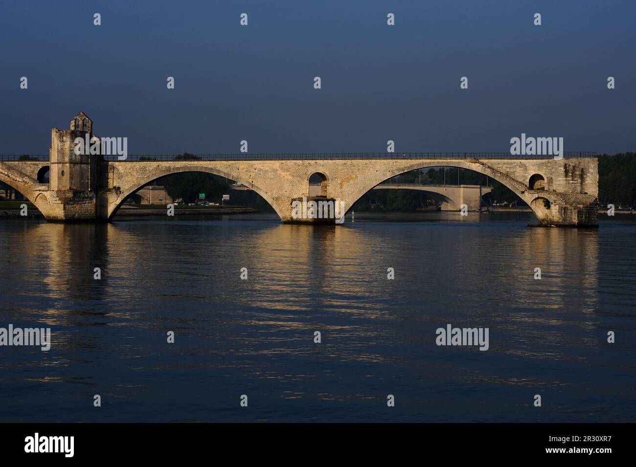 Il Pont d’Avignon o Pont Saint-Bénézet, un ponte medievale sul fiume Rhône ad Avignone, capitale del dipartimento del Vaucluse nella regione della Provenza-Alpi-Côte Azzurra. Sulla sinistra si trova la cappella di Saint-Bénézet o San Nicola. Sia il Pont d'Avignon che la sua cappella furono costruiti alla fine degli anni '1100s in stile romanico provenzale, anche se la cappella fu ridisegnata più tardi. Il ponte è dichiarato patrimonio dell'umanità dall'UNESCO. Questa fotografia è stata scattata una mattina all'inizio di luglio, tra le 7am:8am e le 17:00. Foto Stock