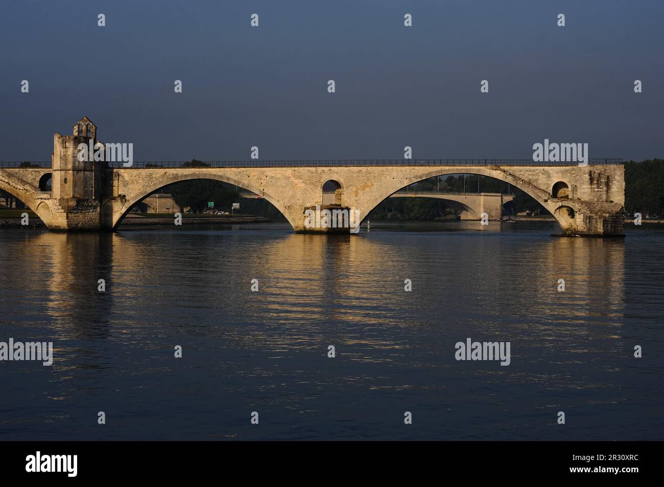 Il Pont d’Avignon o Pont Saint-Bénézet medievale sul fiume Rhône con, sulla sinistra, la cappella di Saint-Bénézet o San Nicola. Sia il ponte che la cappella furono costruiti alla fine degli anni '1100s in stile romanico provenzale, anche se la cappella fu ridisegnata più tardi. Ad Avignone, capitale del dipartimento Vaucluse, nella regione Francia Provenza-Alpi-Côte Azzurra. Il ponte è dichiarato patrimonio dell'umanità dall'UNESCO. Questa fotografia è stata scattata una mattina all'inizio di luglio, tra le 7am:8am e le 17:00. Foto Stock