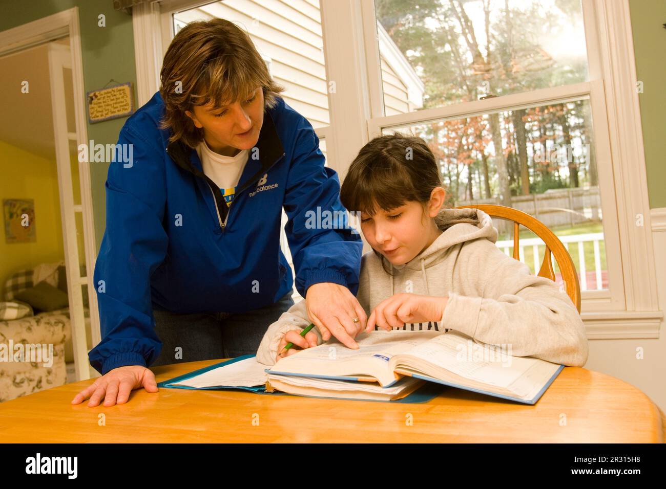 Una madre aiuta la figlia di dieci anni con i compiti a casa. Foto Stock