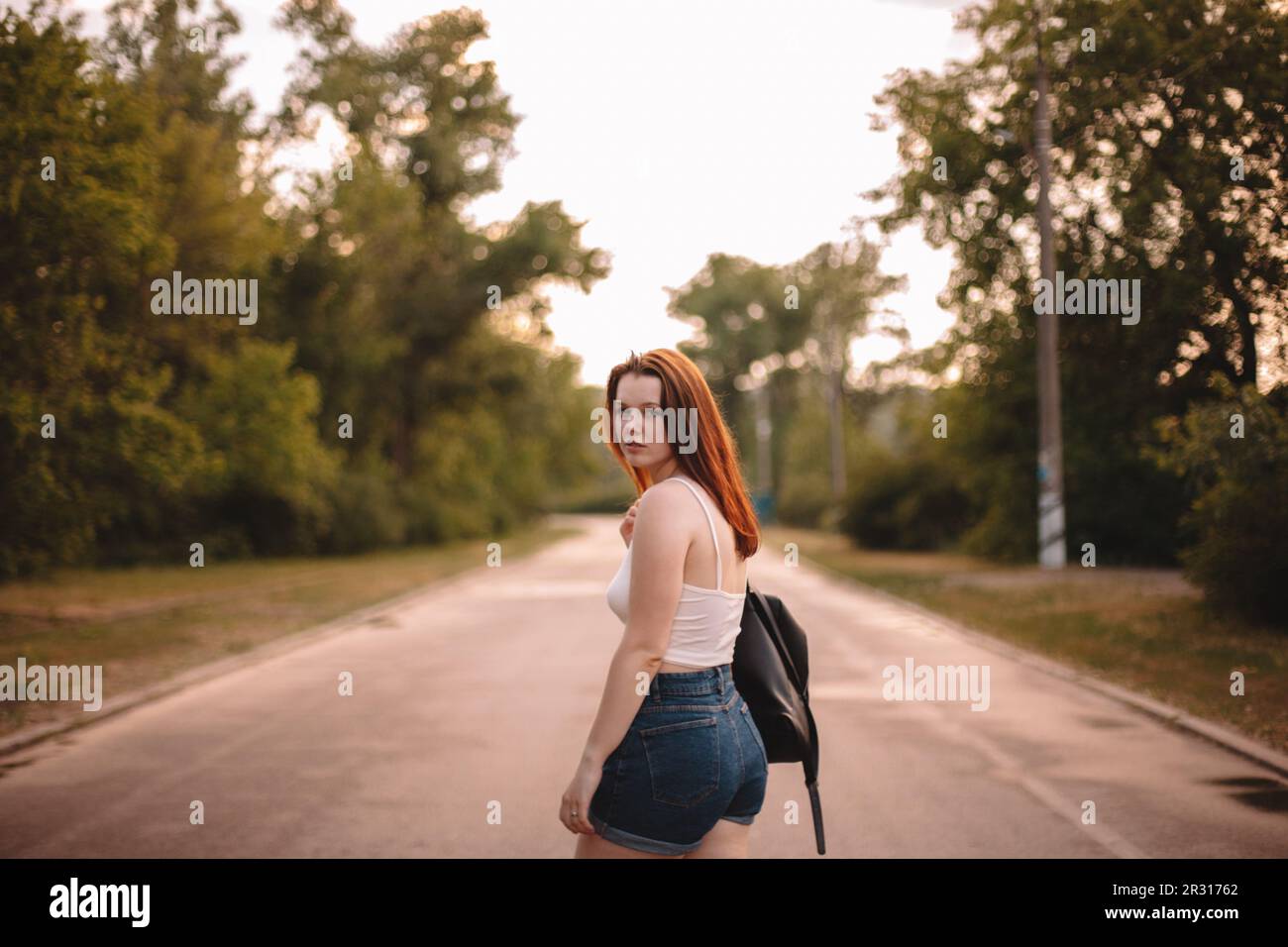 Giovane donna che cammina sulla strada di campagna durante l'estate Foto Stock