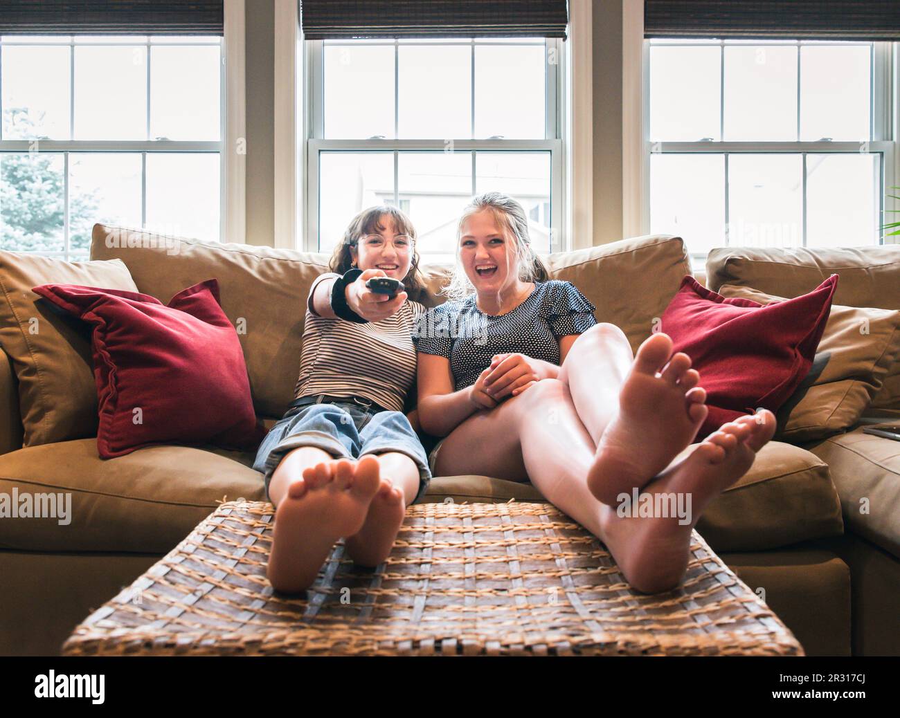 Due ragazze adolescenti sedute su un divano con i piedi in alto guardando la tv. Foto Stock
