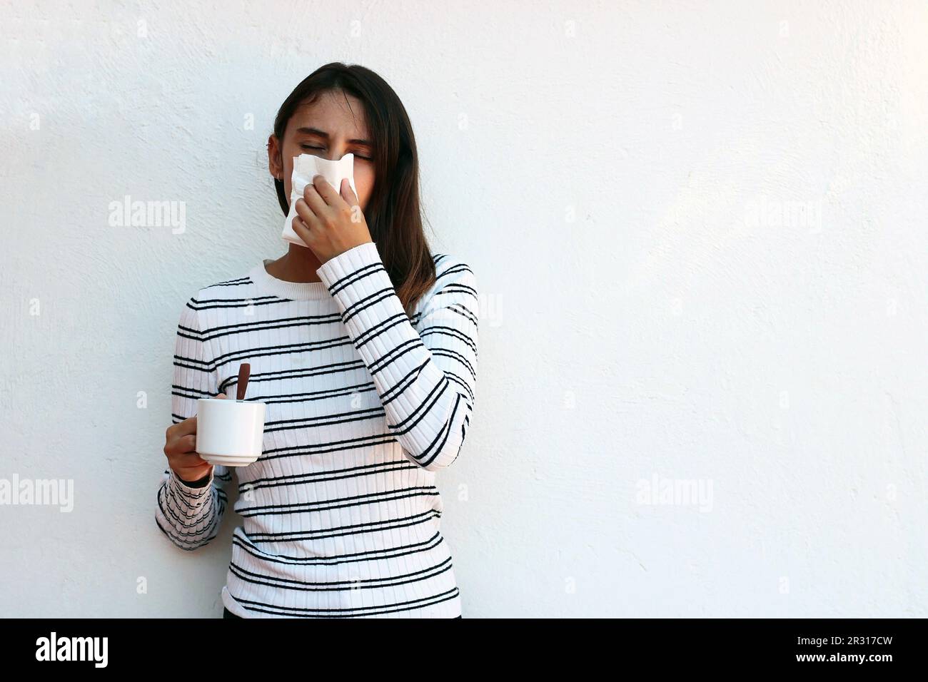 Concetto di salute e medicina - giovane donna che soffia il naso nel tessuto. Foto Stock