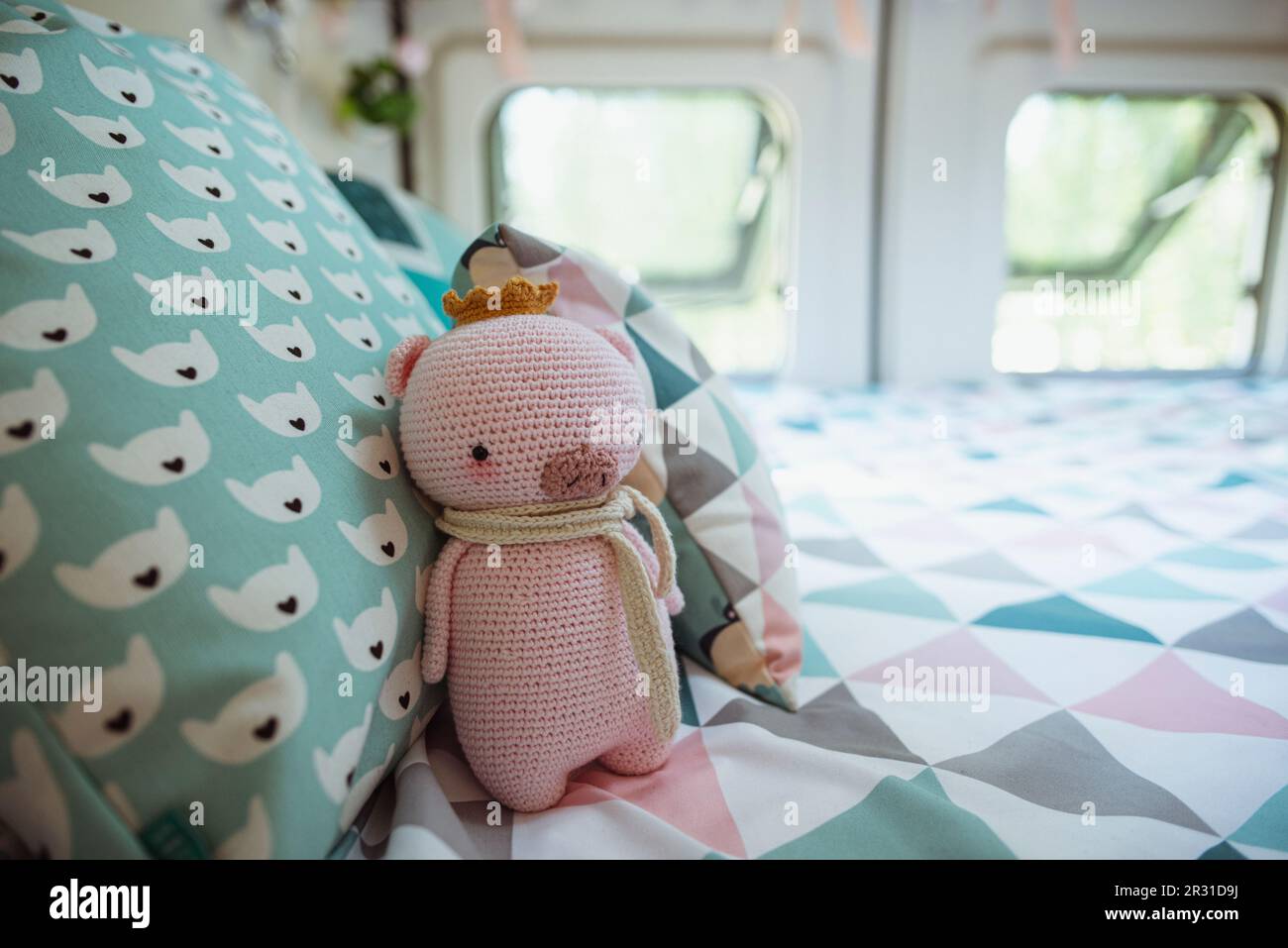 Primo piano di un maiale a crochet fatto in casa (Amigurumi) su un letto in un camper furgone Foto Stock
