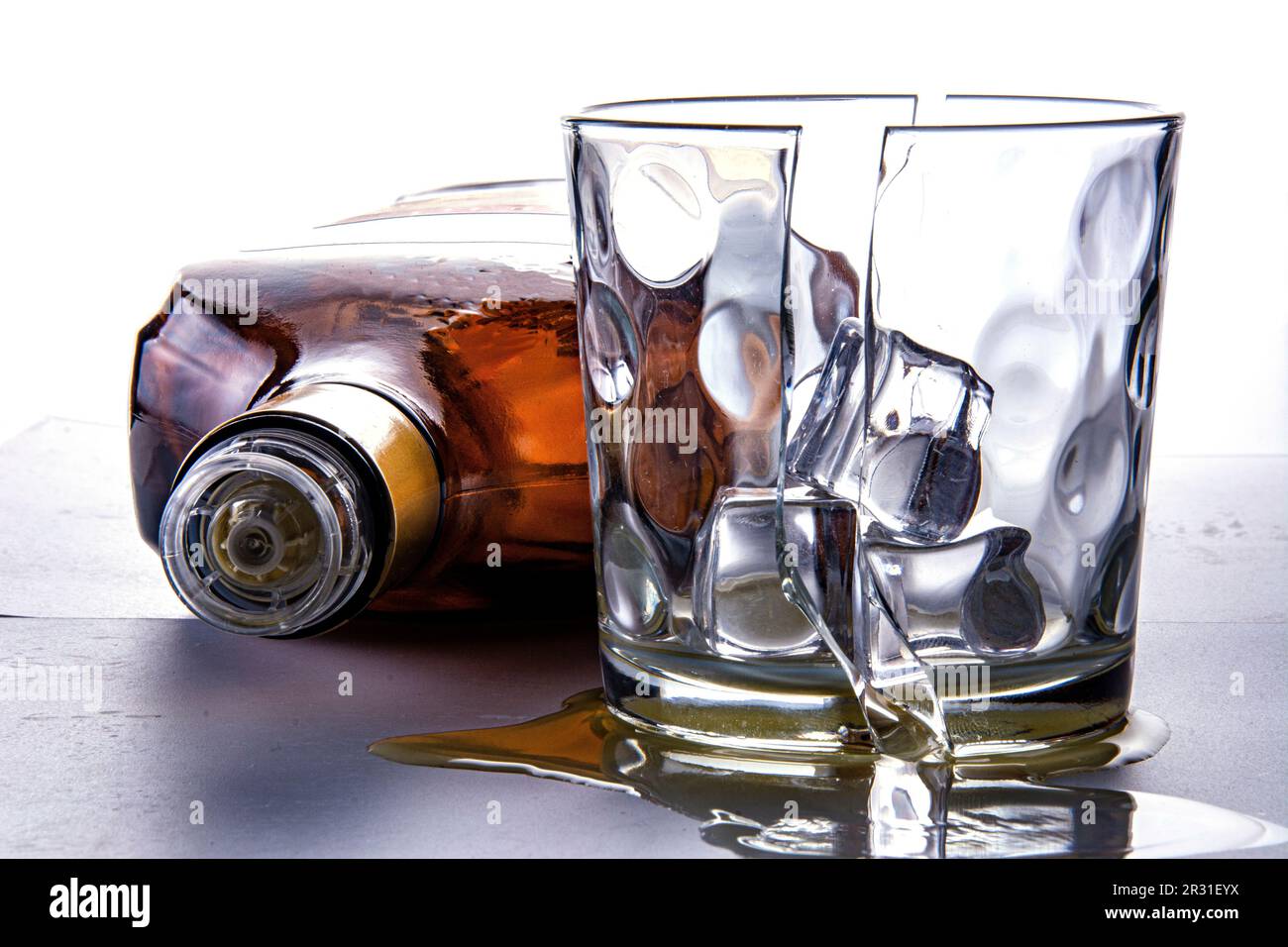 Bottiglia di rum vuota e bicchiere rotto in due metà con tre cubetti di ghiaccio. Fotografato su sfondo bianco nello studio. Ancora la vita al buio. Foto Stock