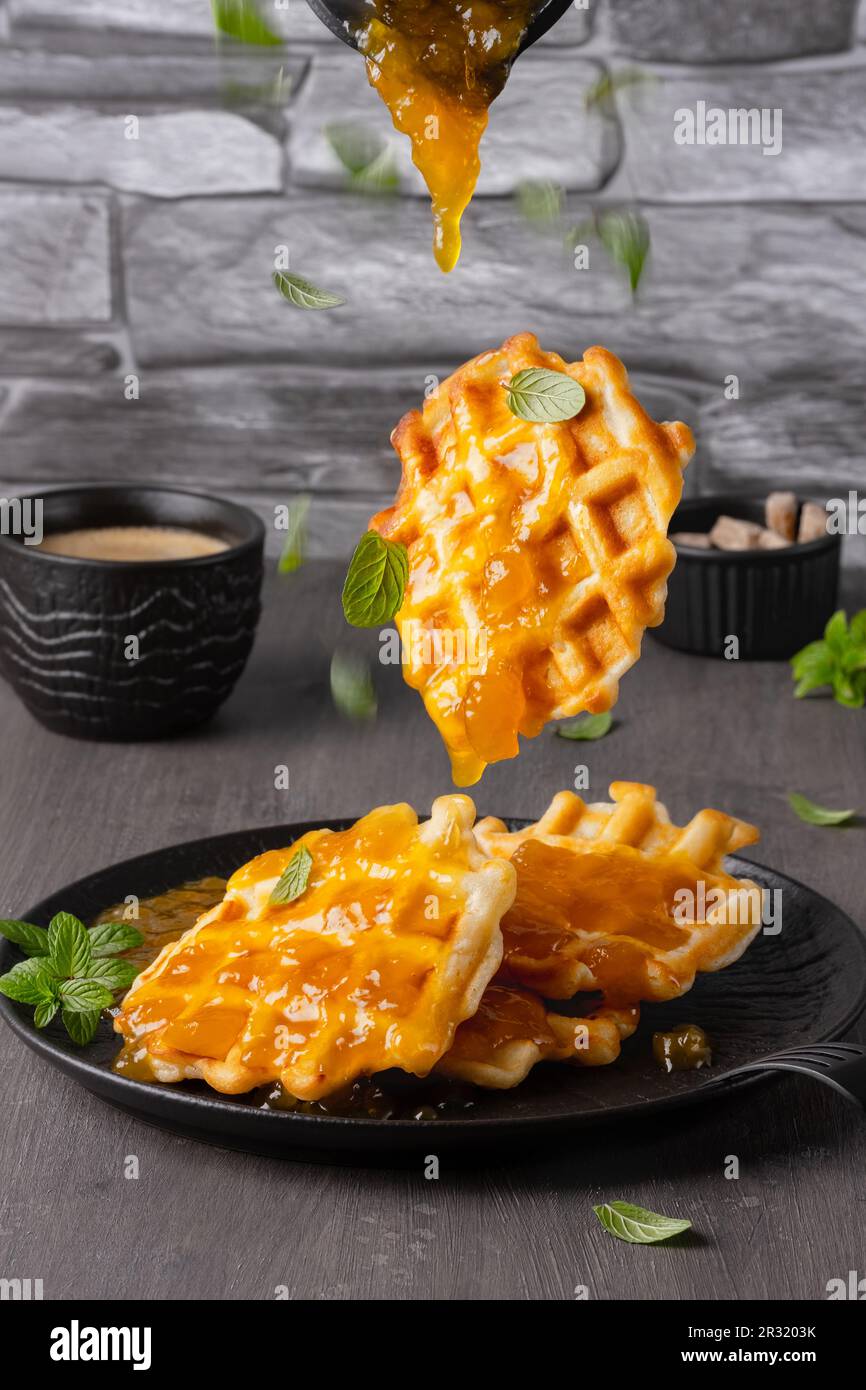 Cialde volanti e menta caduti con marmellata di mango uno sfondo grigio Foto Stock